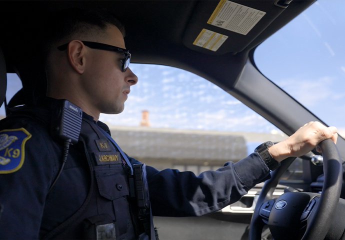 A Waterbury police officer in sunglasses drives a patrol car