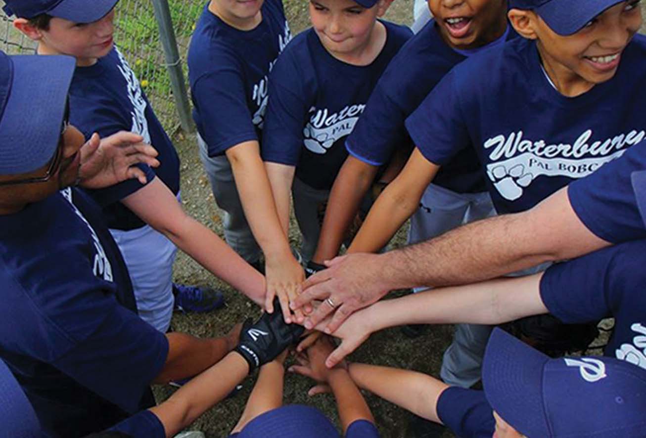 Young boys in baseball uniforms in a huddle with their hands together