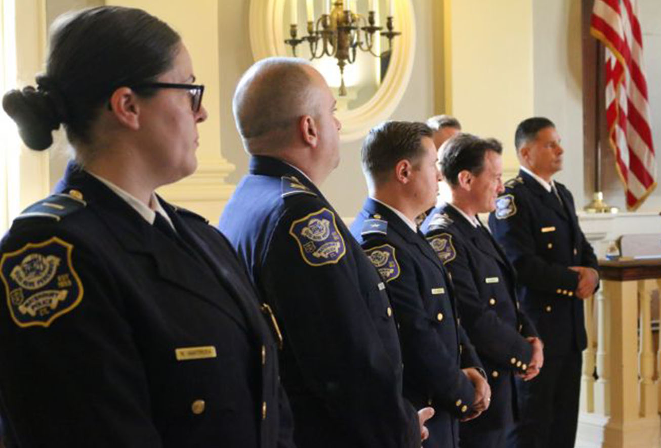 Five Waterbury Police officers in uniform standing in a line indoors