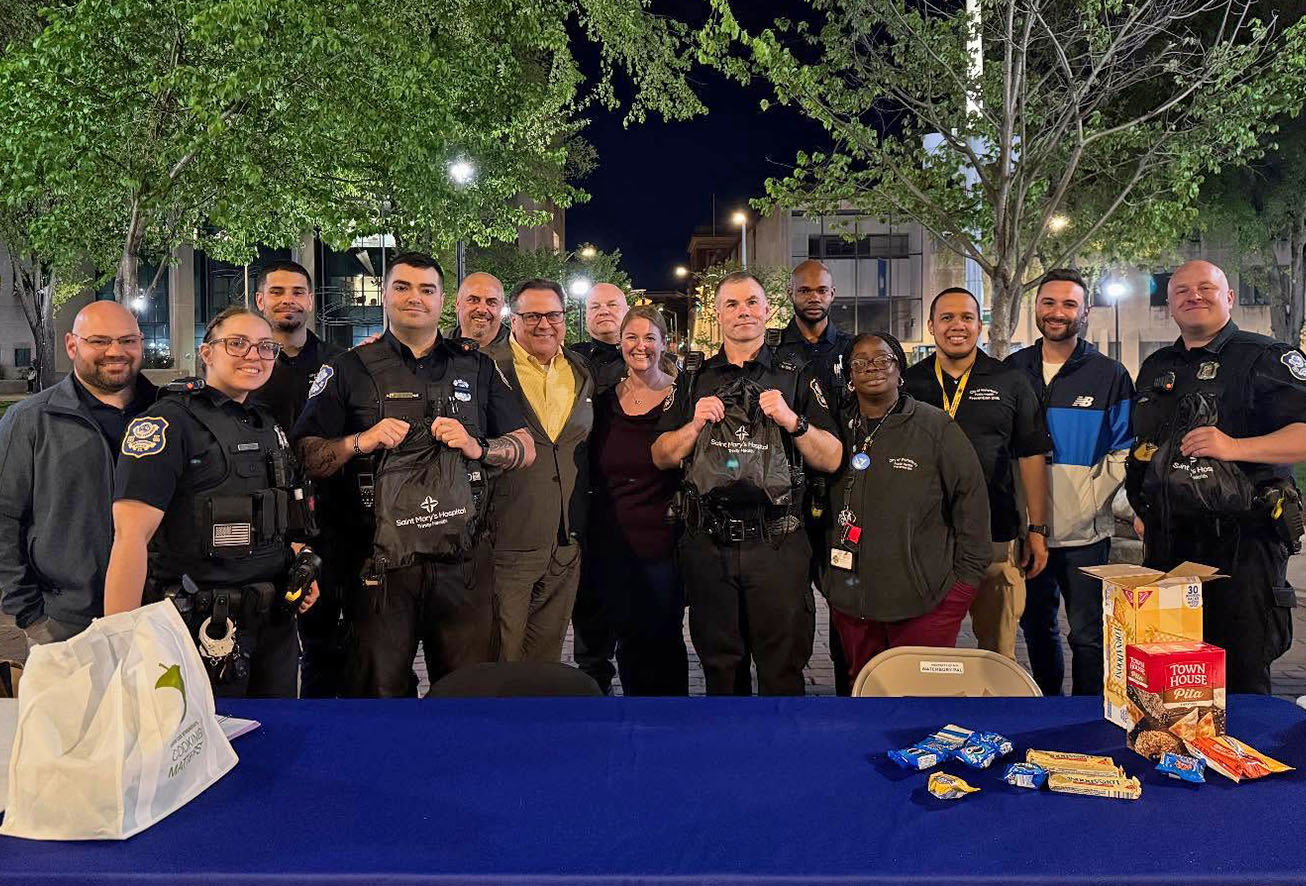 A group of Waterbury police officers and community members posing for a photo at a nighttime outreach event