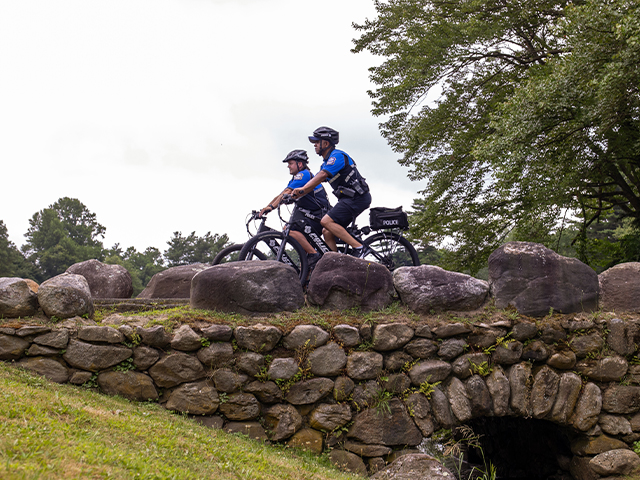Two waterbury PD officers riding bikes over a bridge