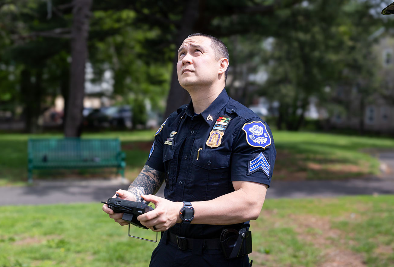 A Waterbury police officer from the drone unit operating a controller outdoors in a park
