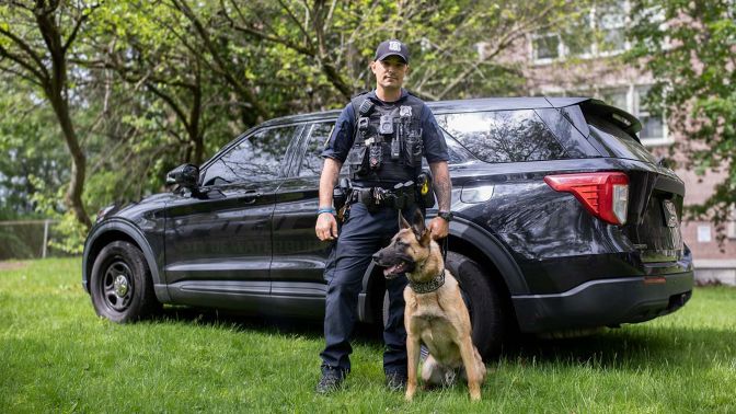 Waterbury police officer and his K-9 partner standing next to a police SUV